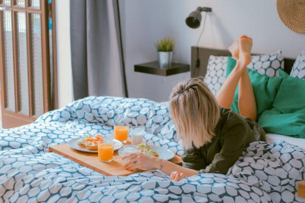 Junge Frau mit Frühstück im Bett